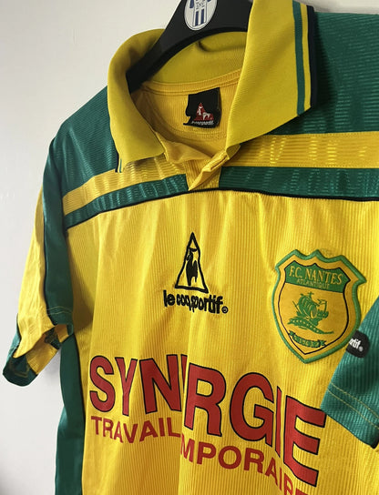 Maillot de foot vintage domicile du FC Nantes de la saison 2001/2002. On peut retrouver l'équipementier Le Coq Sportif et le sponsor Synergie. Il s'agit d'un maillot authentique d'époque.