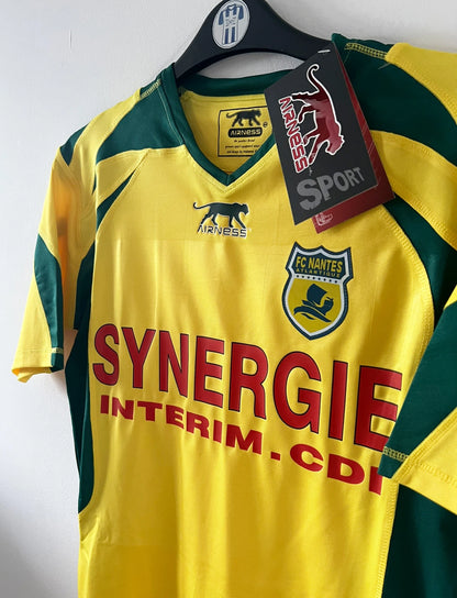 Maillot de foot vintage domicile jaune et vert du FC Nantes de la saison 2006/2007. On peut retrouver l'équipementier Airness et le sponsor Synergie. Il s'agit d'un maillot authentique d'époque.