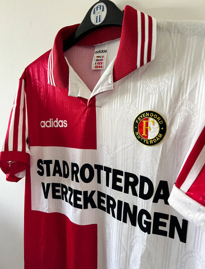 Maillot de foot vintage domicile rouge et blanc de Feyenoord de la saison 1996/1997. On peut retrouver l'équipementier Adidas et le sponsor Stad Rotterdam Verzekeringer. Il s'agit d'un maillot authentique d'époque.