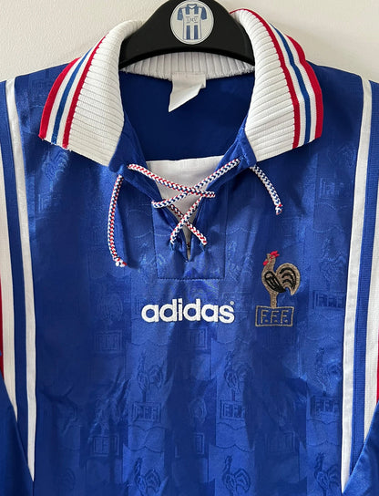 Maillot de foot vintage domicile bleu de l'Equipe de France 1996. On peut retrouver l'équipementier Adidas. Il s'agit d'un maillot authentique d'époque.