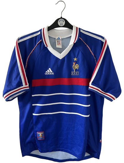 Maillot de foot vintage domicile bleu de l'équipe de France 1998. On peut retrouver l'équipementier Adidas. Il s'agit d'un maillot authentique d'époque.