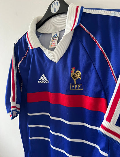 Maillot de foot vintage domicile bleu blanc et rouge de l'équipe de france 1998. On peut retrouver l'équipementier Adidas. Il s'agit d'un maillot authentique d'époque.
