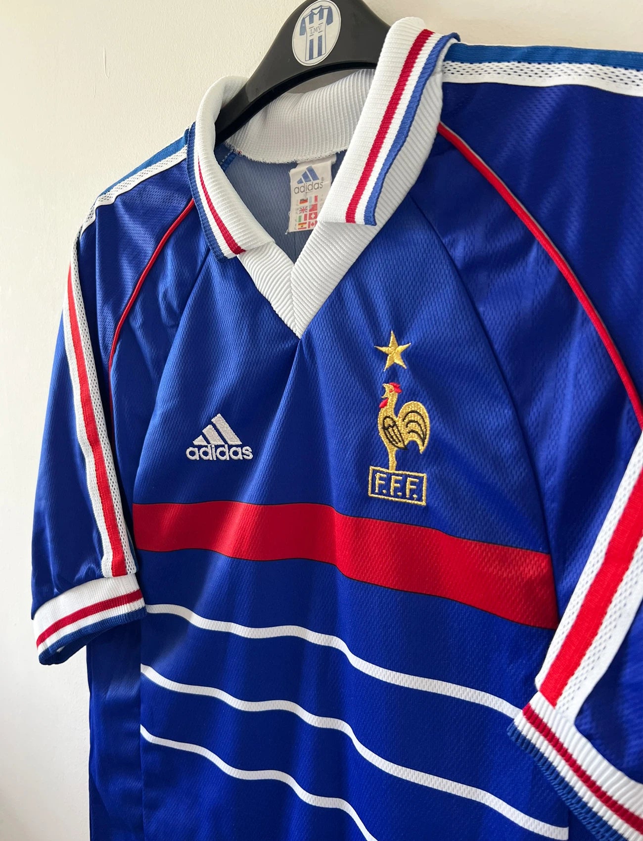 Maillot de foot vintage domicile bleu de l'équipe de france 1998. On peut retrouver l'équipementier Adidas. Le maillot est floqué du numéro 10 Zinedine Zidane. Il s'agit d'un maillot authentique d'époque.