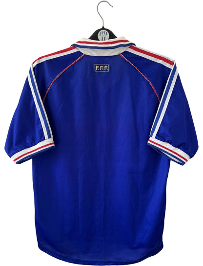 Maillot de foot vintage domicile bleu de l'équipe de France 1998. On peut retrouver l'équipementier Adidas. Il s'agit d'un maillot authentique d'époque.