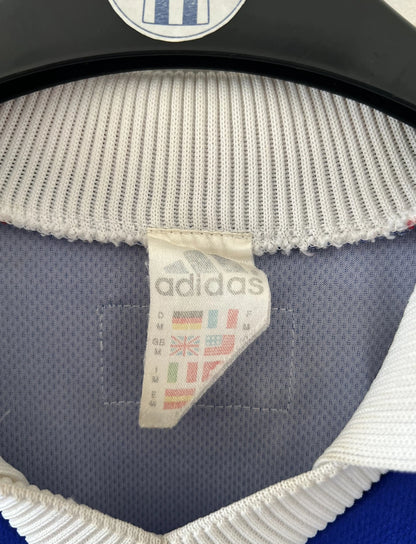 Maillot de foot vintage domicile bleu de l'équipe de France 1998. On peut retrouver l'équipementier Adidas. Il s'agit d'un maillot authentique d'époque.