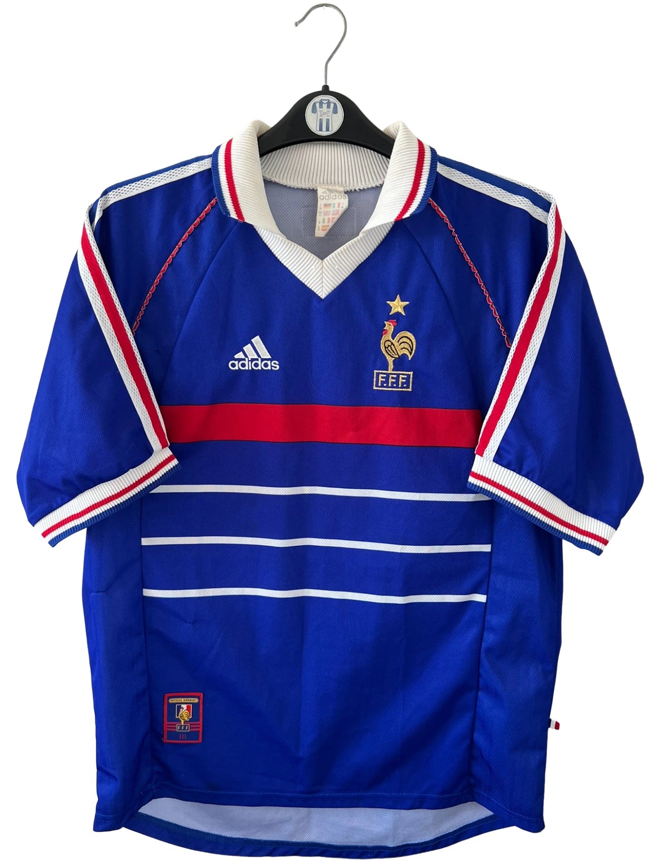 Maillot de foot vintage domicile bleu de l'équipe de France 1998. On peut retrouver l'équipementier Adidas. Il s'agit d'un maillot authentique d'époque.