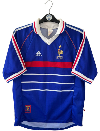 Maillot de foot vintage domicile bleu de l'équipe de France 1998. On peut retrouver l'équipementier Adidas. Il s'agit d'un maillot authentique d'époque.