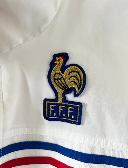 Veste de foot vintage blanche de l'Equipe de France 1998. On peut retrouver l'équipementier Adidas. Il s'agit d'un maillot authentique d'époque.