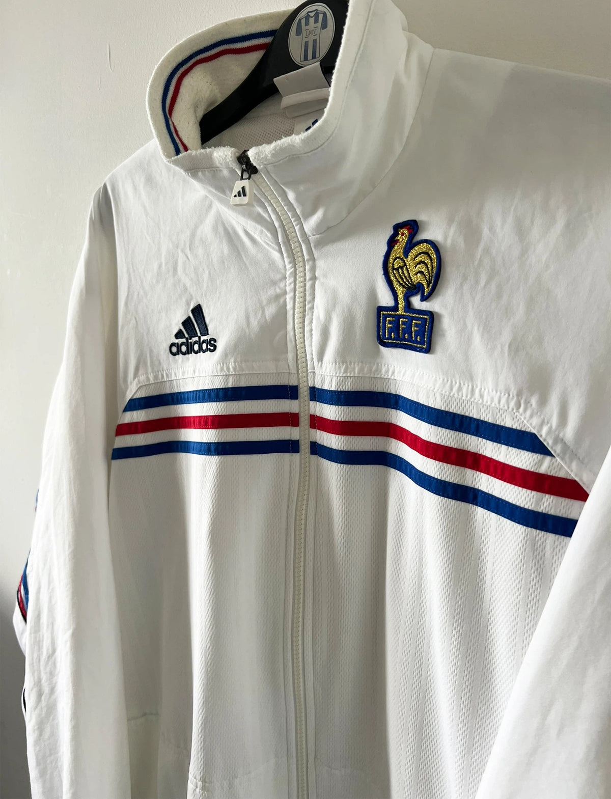 Veste de foot vintage blanche de l'Equipe de France 1998. On peut retrouver l'équipementier Adidas. Il s'agit d'un maillot authentique d'époque.