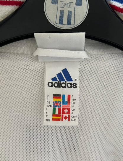 Veste de foot vintage blanche de l'Equipe de France 1998. On peut retrouver l'équipementier Adidas. Il s'agit d'un maillot authentique d'époque.
