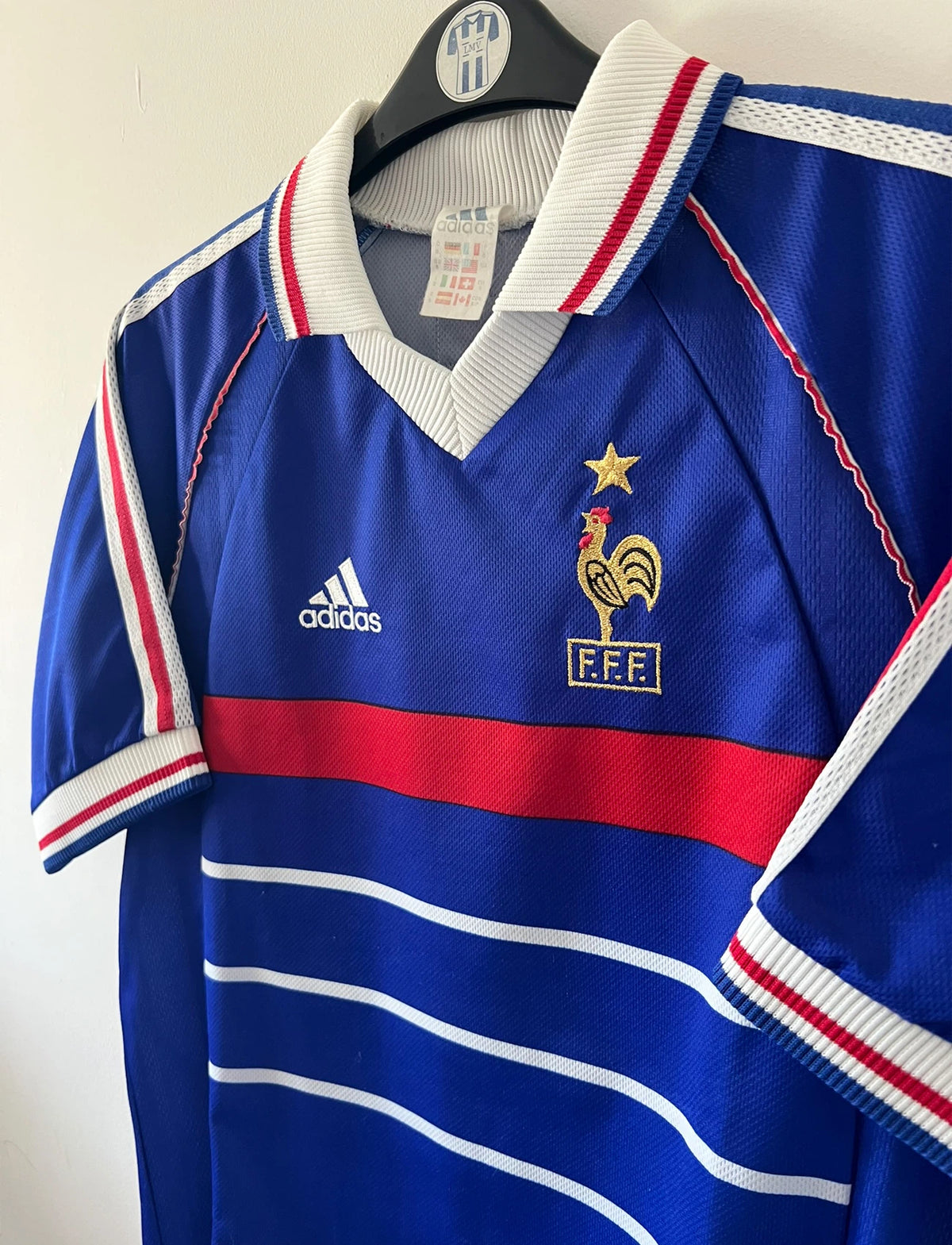 Maillot foot vintage domicile equipe de france 1998 bleu blanc et rouge. On peut retrouver l'équipementier adidas. Le maillot est floqué du numéro 10 Zinedine Zidane. Il s'agit d'un maillot authentique d'époque avec la signature de Zidane en sérigraphié.