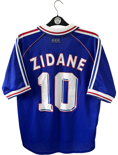 Maillot foot vintage domicile equipe de france 1998 bleu blanc et rouge. On peut retrouver l'équipementier adidas. Le maillot est floqué du numéro 10 Zinedine Zidane. Il s'agit d'un maillot authentique d'époque vendu avec son short d'époque.