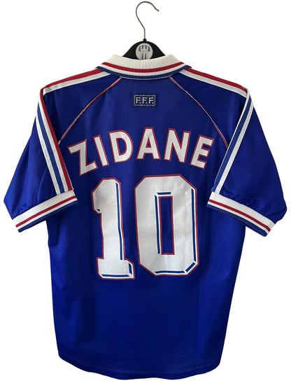 Maillot foot vintage domicile equipe de france 1998 bleu blanc et rouge. On peut retrouver l'équipementier adidas. Le maillot est floqué du numéro 10 Zinedine Zidane. Il s'agit d'un maillot authentique d'époque avec la signature de Zidane en sérigraphié.