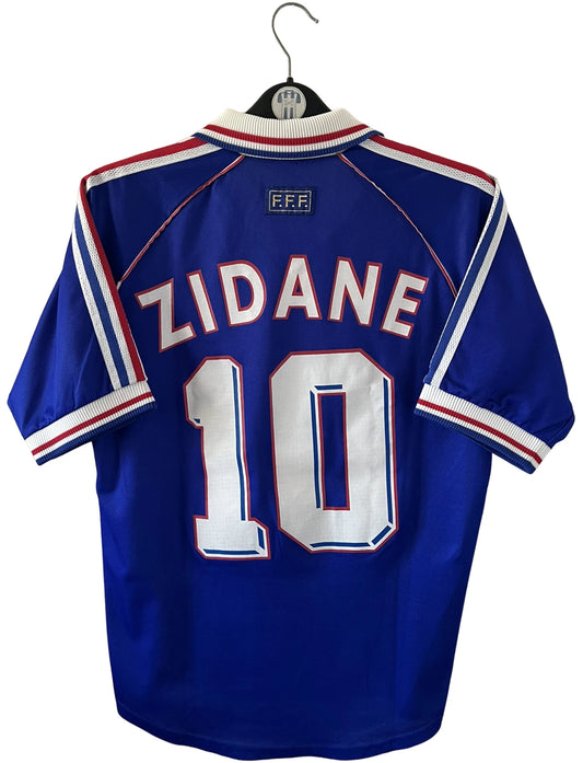 Maillot foot vintage domicile equipe de france 1998 bleu blanc et rouge. On peut retrouver l'équipementier adidas. Le maillot est floqué du numéro 10 Zinedine Zidane. Il s'agit d'un maillot authentique d'époque avec la signature de Zidane en sérigraphié.