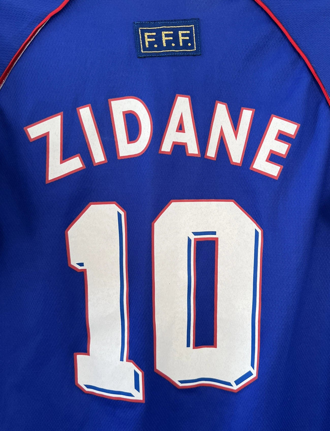 Maillot de foot vintage domicile de l'équipe de france 1998 bleu. On peut retrouver l'équipementier adidas. Le maillot est floqué du numéro 10 Zinedine Zidane. Il s'agit d'un maillot authentique d'époque.