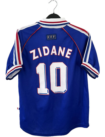 Maillot de foot vintage domicile de l'équipe de france 1998 bleu. On peut retrouver l'équipementier adidas. Le maillot est floqué du numéro 10 Zinedine Zidane. Il s'agit d'un maillot authentique d'époque.