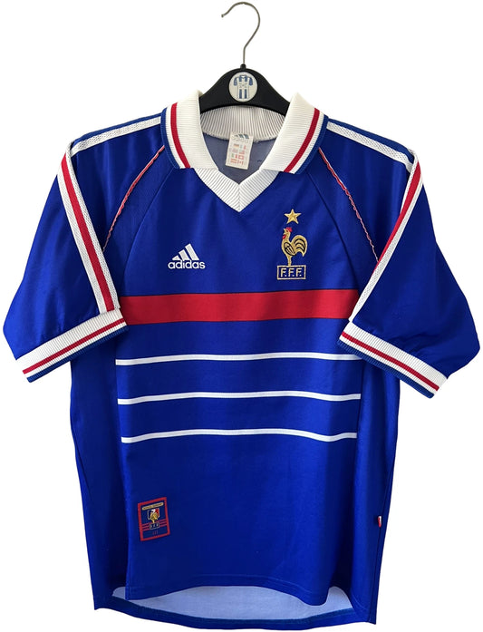 Maillot foot vintage domicile equipe de france 1998 bleu blanc et rouge. On peut retrouver l'équipementier adidas. Le maillot est floqué du numéro 10 Zinedine Zidane. Il s'agit d'un maillot authentique d'époque avec la signature de Zidane en sérigraphié.