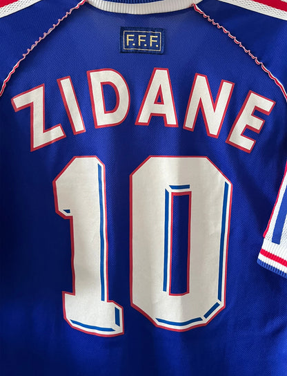 Maillot foot vintage domicile equipe de france 1998 bleu blanc et rouge. On peut retrouver l'équipementier adidas. Ils 'agit d'un maillot authentique d'époque floqué Zinedine Zidane
