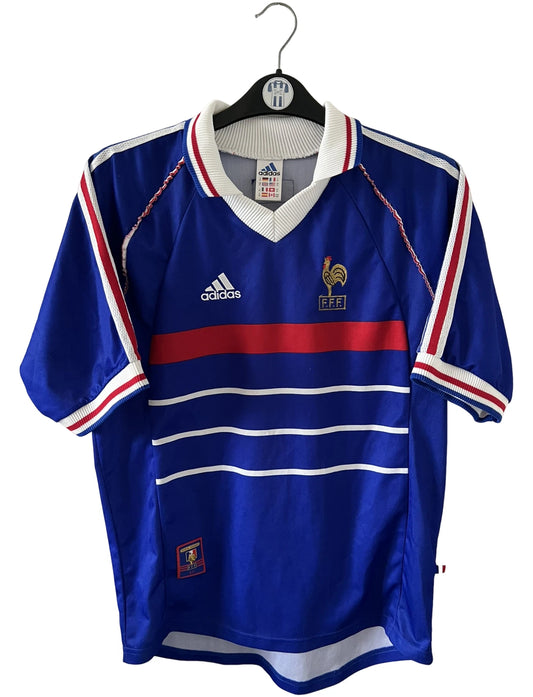Maillot de foot vintage domicile bleu blanc et rouge de l'équipe de france 1998. On peut retrouver l'équipementier Adidas. Il s'agit d'un maillot authentique d'époque.