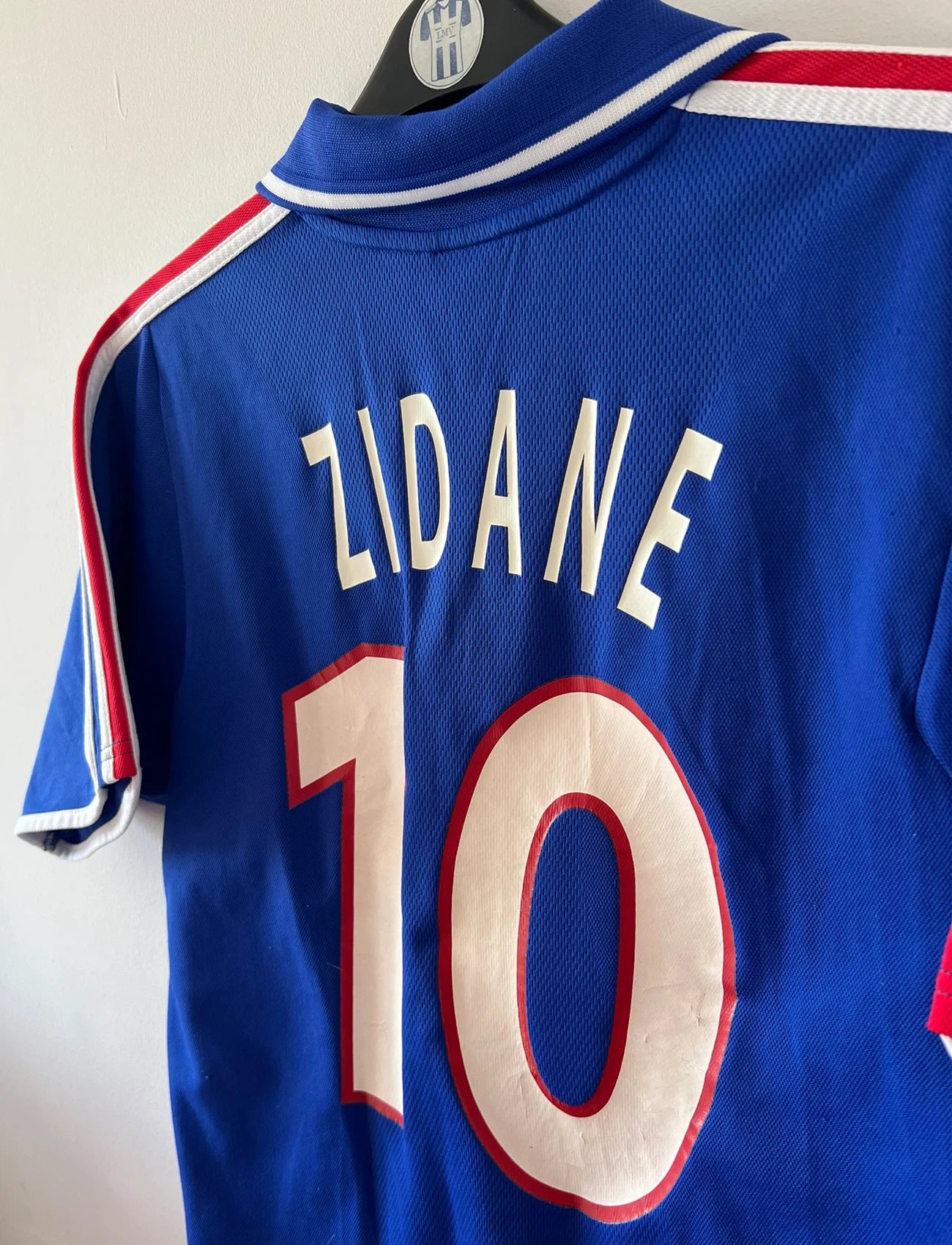 Maillot de foot vintage domicile bleu de l'équipe de france 2000. On peut retrouver l'équipementier Adidas. Le maillot est floqué du numéro 10 Zidane. Il s'agit d'un maillot authentique d'époque.