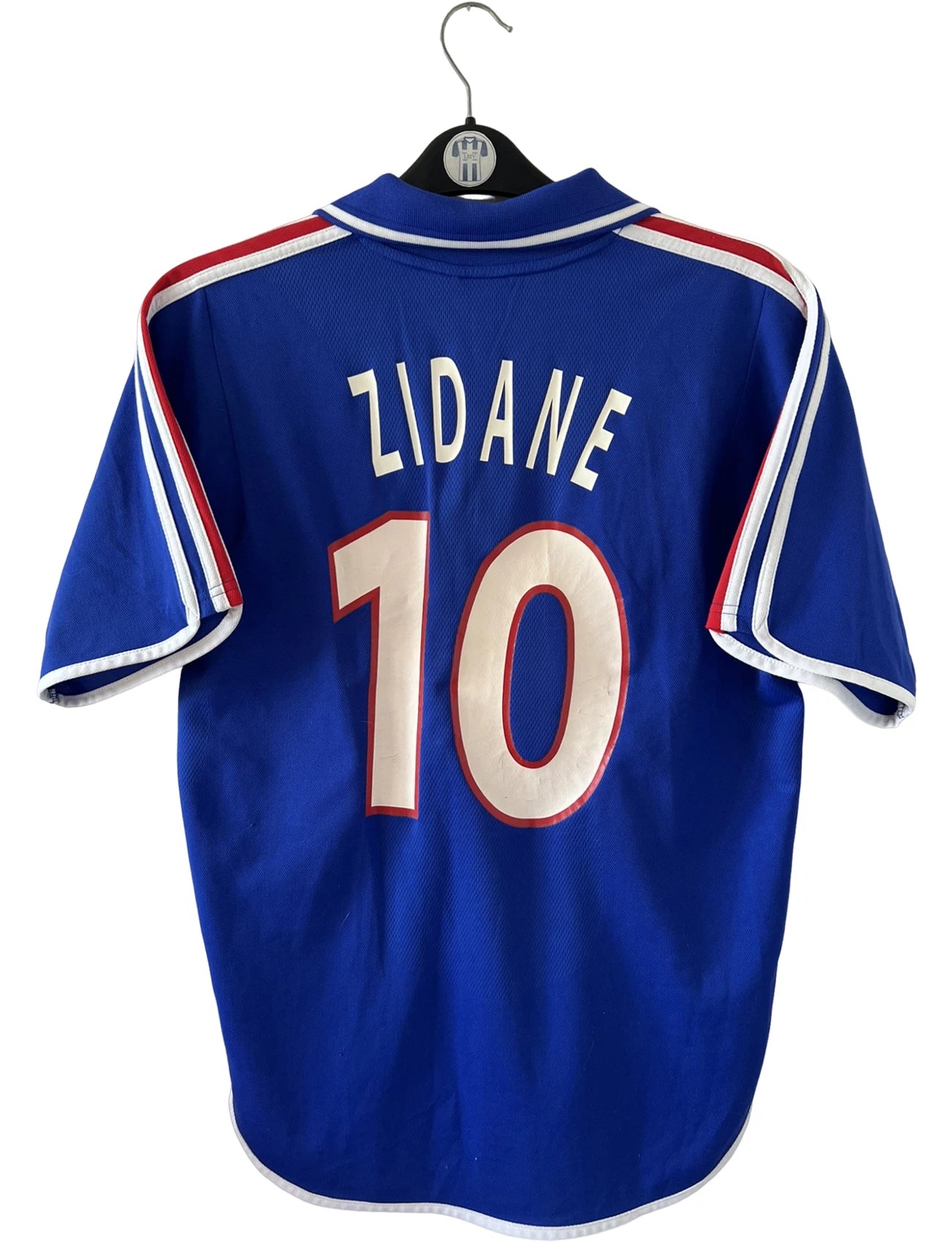 Maillot de foot vintage domicile bleu de l'équipe de france 2000. On peut retrouver l'équipementier Adidas. Le maillot est floqué du numéro 10 Zidane. Il s'agit d'un maillot authentique d'époque.