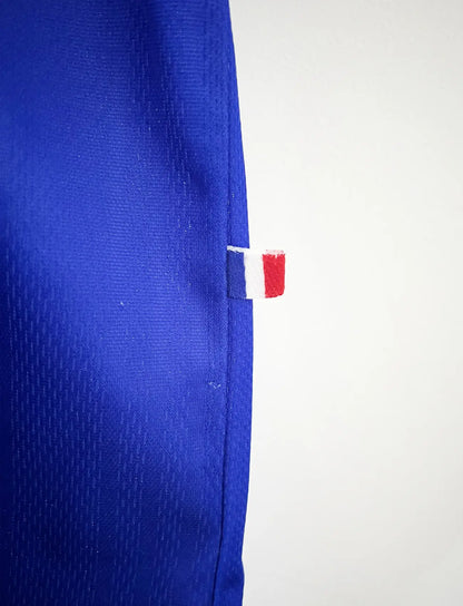 Maillot de foot vintage bleu, blanc et rouge de l'équipe de france 1998. On peut retrouver l'équipementier adidas. Il s'agit d'un maillot authentique édité avant la finale de la coupe du monde car celui-ci ne possède pas l'étoile.