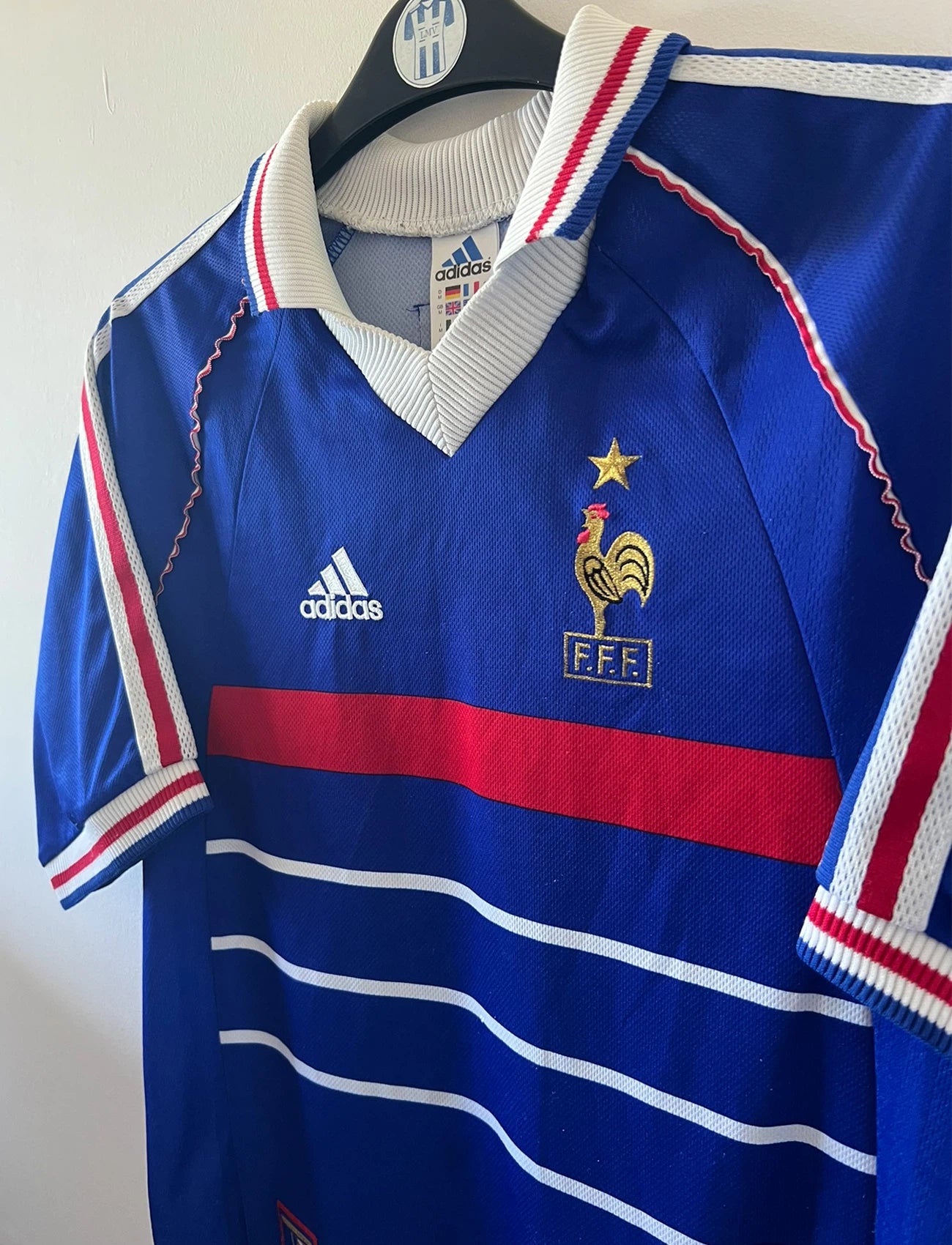 Maillot de foot vintage domicile bleu de l'équipe de france 1998. On peut retrouver l'équipementier Adidas. Le maillot est floqué du numéro 10 Zinedine Zidane. Il s'agit d'un maillot authentique d'époque.
