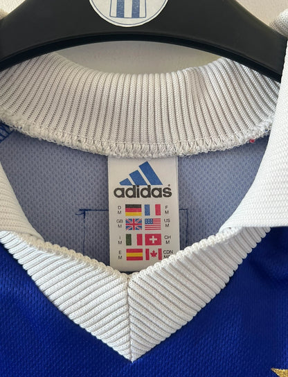 Maillot de foot vintage domicile bleu de l'équipe de france 1998. On peut retrouver l'équipementier Adidas. Le maillot est floqué du numéro 10 Zinedine Zidane. Il s'agit d'un maillot authentique d'époque.