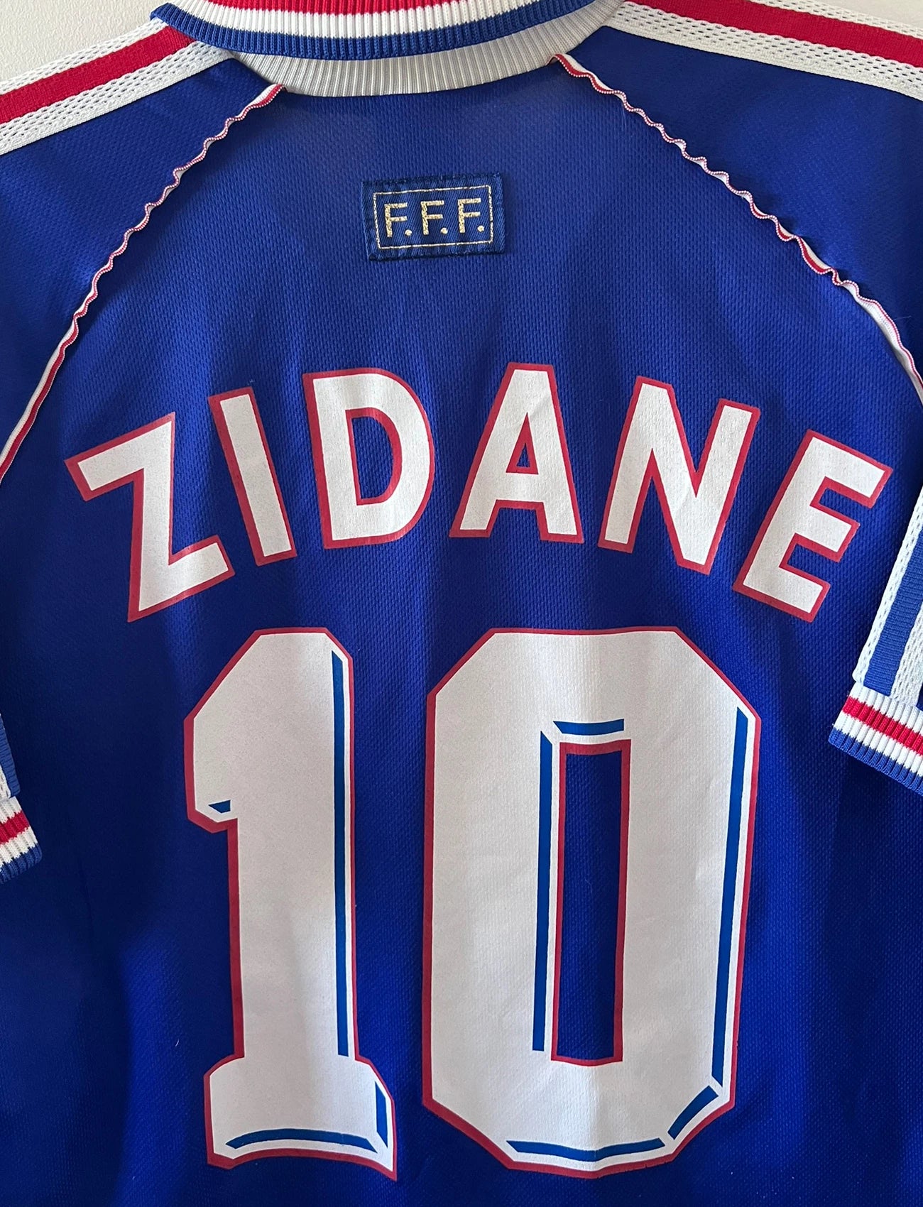 Maillot de foot vintage domicile bleu de l'équipe de france 1998. On peut retrouver l'équipementier Adidas. Le maillot est floqué du numéro 10 Zinedine Zidane. Il s'agit d'un maillot authentique d'époque.