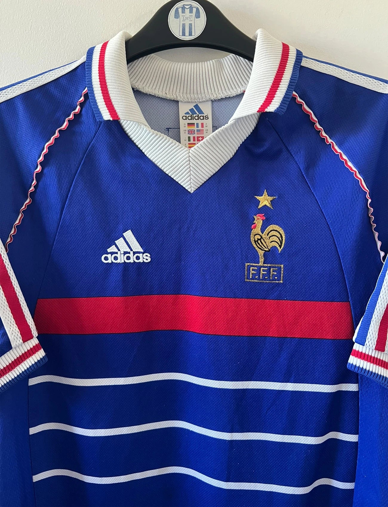 Maillot de foot vintage domicile bleu de l'équipe de france 1998. On peut retrouver l'équipementier Adidas. Le maillot est floqué du numéro 10 Zinedine Zidane. Il s'agit d'un maillot authentique d'époque.