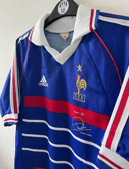 Maillot de foot vintage domicile bleu de l'équipe de france 1998. On peut retrouver l'équipementier Adidas. Le maillot est floqué du numéro 10 Zinedine Zidane. Il s'agit d'un maillot authentique d'époque.