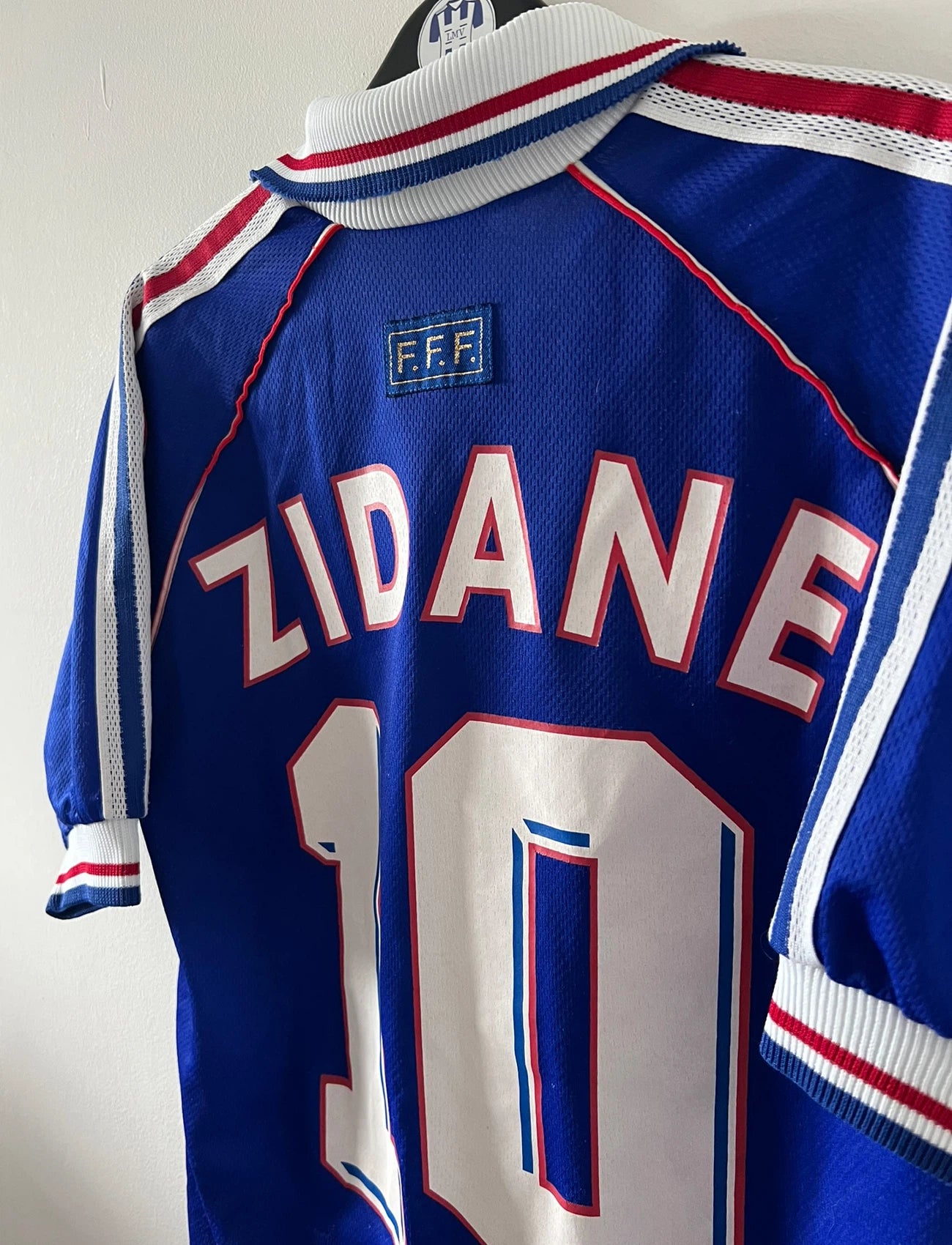 Maillot de foot vintage domicile bleu de l'équipe de france 1998. On peut retrouver l'équipementier Adidas. Le maillot est floqué du numéro 10 Zinedine Zidane. Il s'agit d'un maillot authentique d'époque.