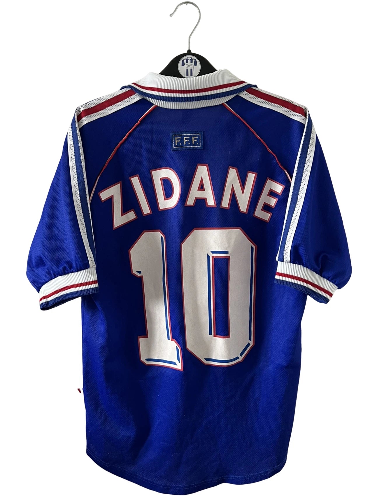 Maillot de foot vintage domicile bleu de l'équipe de france 1998. On peut retrouver l'équipementier Adidas. Le maillot est floqué du numéro 10 Zinedine Zidane. Il s'agit d'un maillot authentique d'époque.