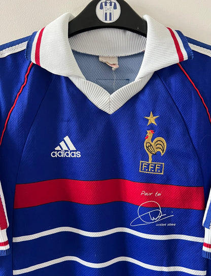 Maillot de foot vintage domicile bleu de l'équipe de france 1998. On peut retrouver l'équipementier Adidas. Le maillot est floqué du numéro 10 Zinedine Zidane. Il s'agit d'un maillot authentique d'époque.