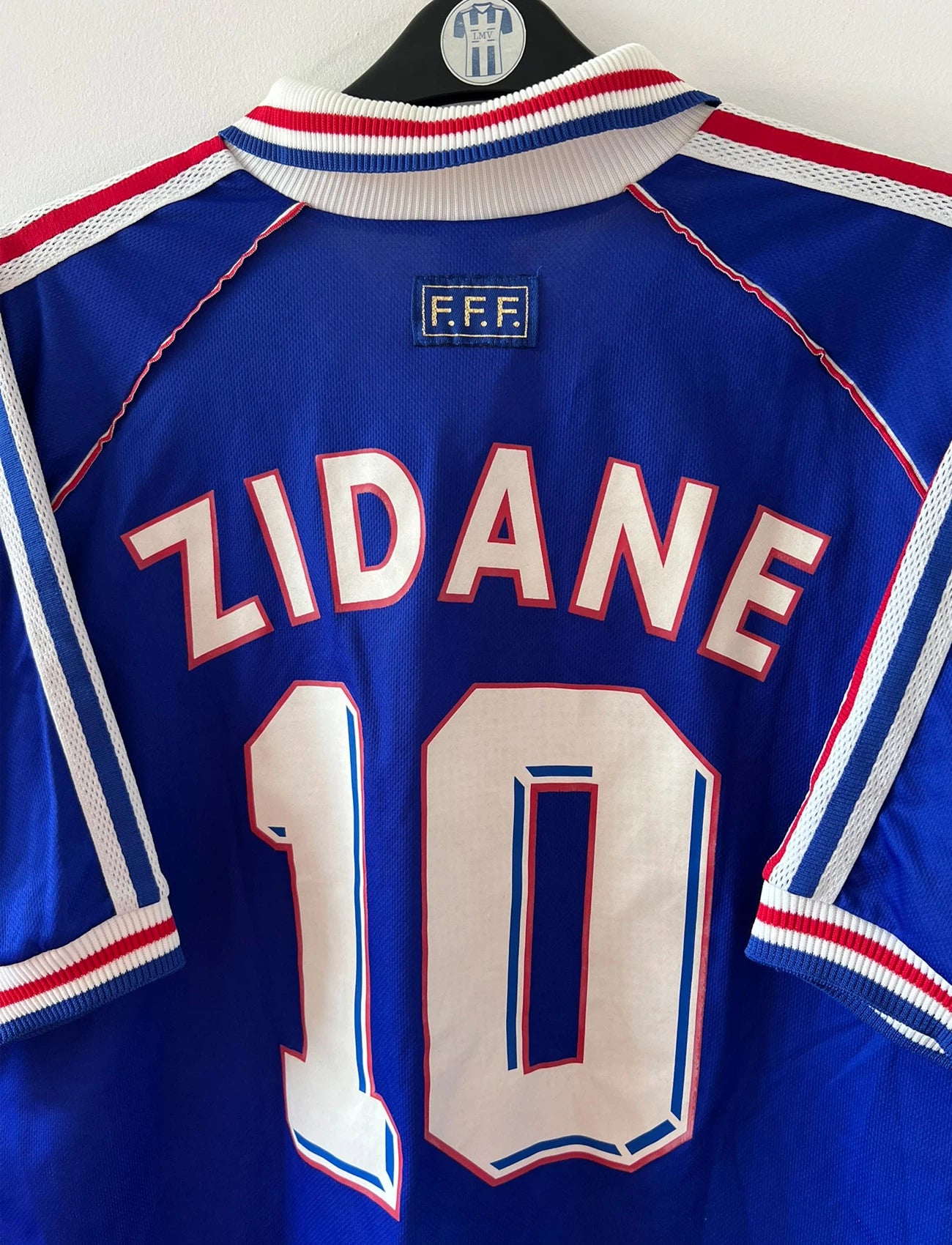 Maillot de foot vintage domicile bleu de l'équipe de France 1998. On peut retrouver l'équipementier Adidas. Le maillot est floqué du numéro 10 Zinedine Zidane. Il s'agit d'un maillot authentique d'époque.