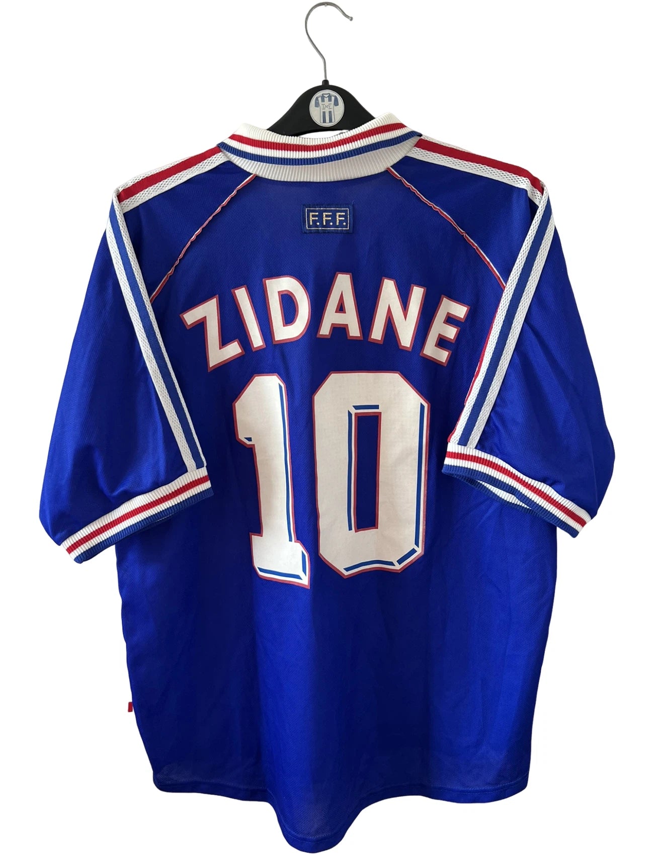 Maillot de foot vintage domicile bleu de l'équipe de France 1998. On peut retrouver l'équipementier Adidas. Le maillot est floqué du numéro 10 Zinedine Zidane. Il s'agit d'un maillot authentique d'époque.