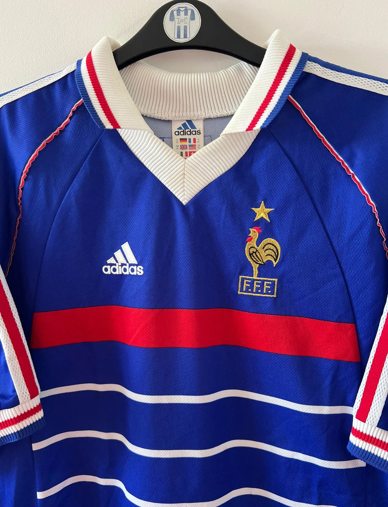 Maillot de foot vintage domicile bleu de l'équipe de France 1998. On peut retrouver l'équipementier Adidas. Le maillot est floqué du numéro 10 Zinedine Zidane. Il s'agit d'un maillot authentique d'époque.
