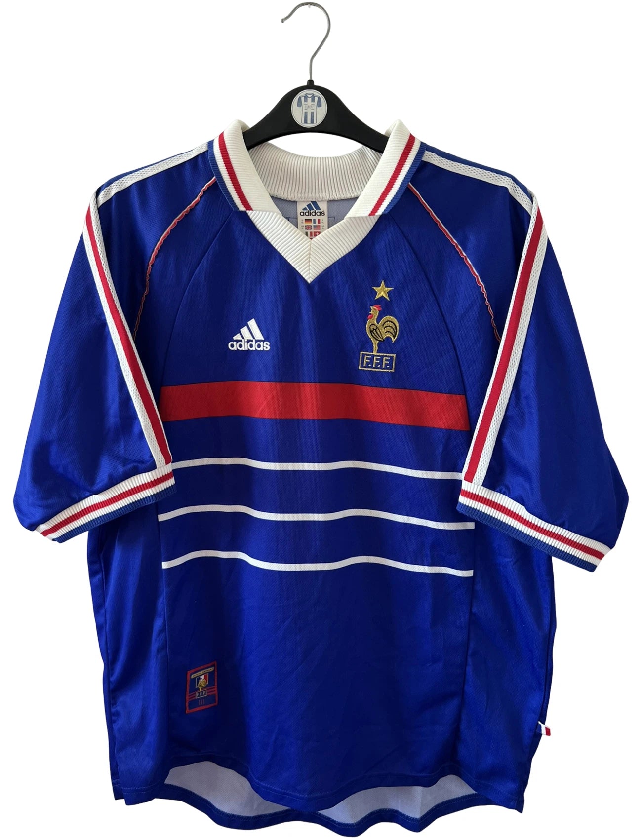 Maillot de foot vintage domicile bleu de l'équipe de France 1998. On peut retrouver l'équipementier Adidas. Le maillot est floqué du numéro 10 Zinedine Zidane. Il s'agit d'un maillot authentique d'époque.