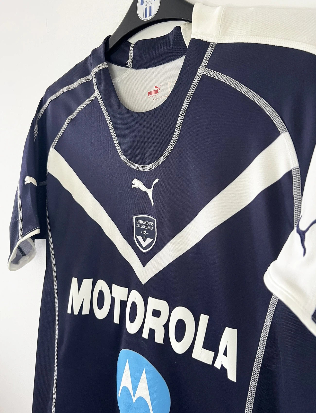 Maillot de foot vintage domicile bleu des Girondins de Bordeaux de la saison 2004-2005. On peut retrouver l'équipementier Puma et le sponsor Motorola. Le maillot est floqué du numéro 24 Mavuba. Il s'agit d'un maillot authentique d'époque.
