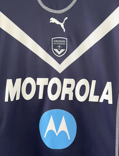 Maillot de foot vintage domicile bleu des Girondins de Bordeaux de la saison 2004-2005. On peut retrouver l'équipementier Puma et le sponsor Motorola. Le maillot est floqué du numéro 24 Mavuba. Il s'agit d'un maillot authentique d'époque.