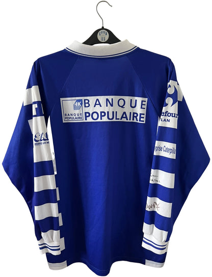 Maillot de foot vintage domicile bleu et blanc de Grenoble de la saison 1999/2000. On peut retrouver l'équipementier Duarig et l'équipementier Sodexho. Il s'agit d'un maillot authentique d'époque.