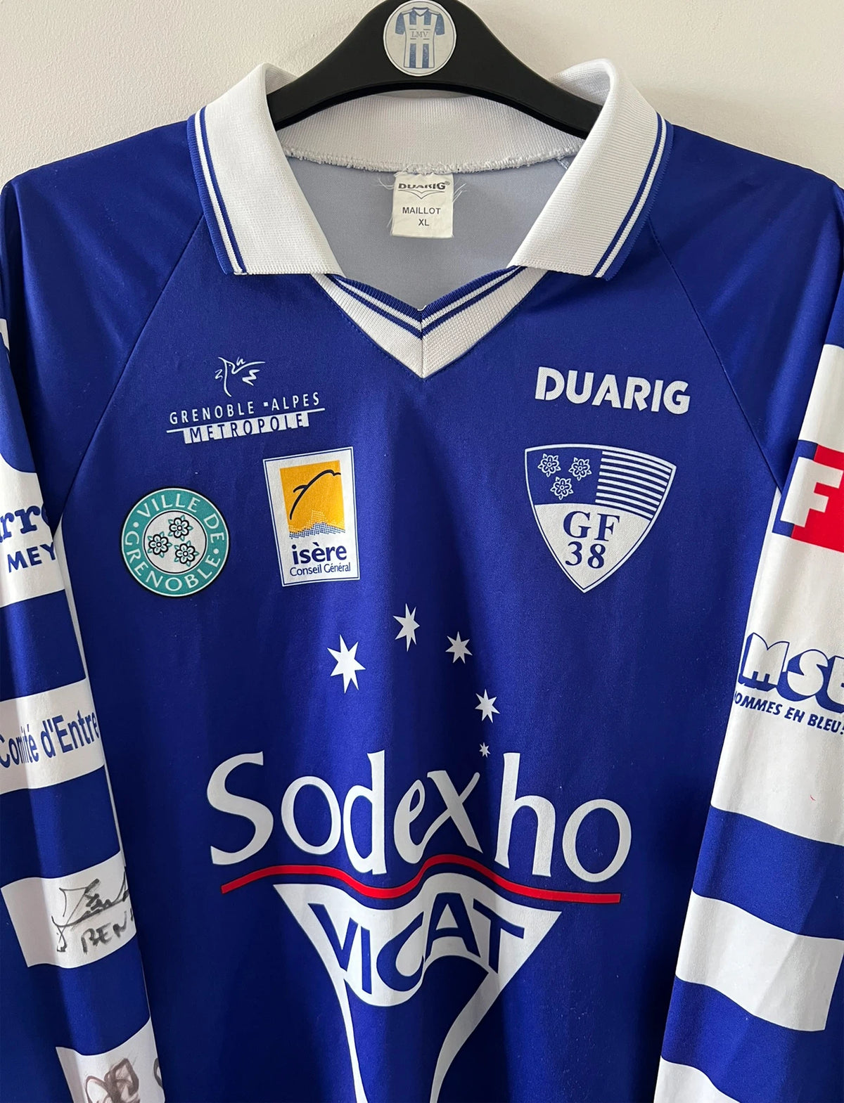 Maillot de foot vintage domicile bleu et blanc de Grenoble de la saison 1999/2000. On peut retrouver l'équipementier Duarig et l'équipementier Sodexho. Il s'agit d'un maillot authentique d'époque.