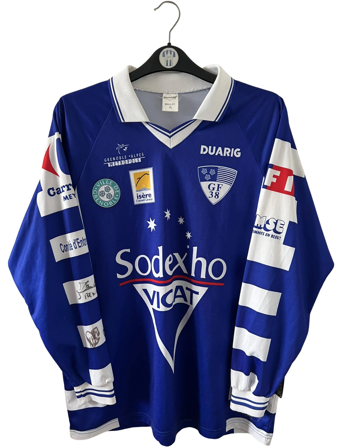 Maillot de foot vintage domicile bleu et blanc de Grenoble de la saison 1999/2000. On peut retrouver l'équipementier Duarig et l'équipementier Sodexho. Il s'agit d'un maillot authentique d'époque.