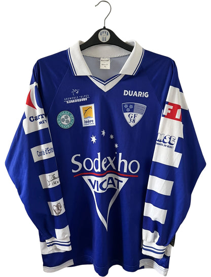 Maillot de foot vintage domicile bleu et blanc de Grenoble de la saison 1999/2000. On peut retrouver l'équipementier Duarig et l'équipementier Sodexho. Il s'agit d'un maillot authentique d'époque.