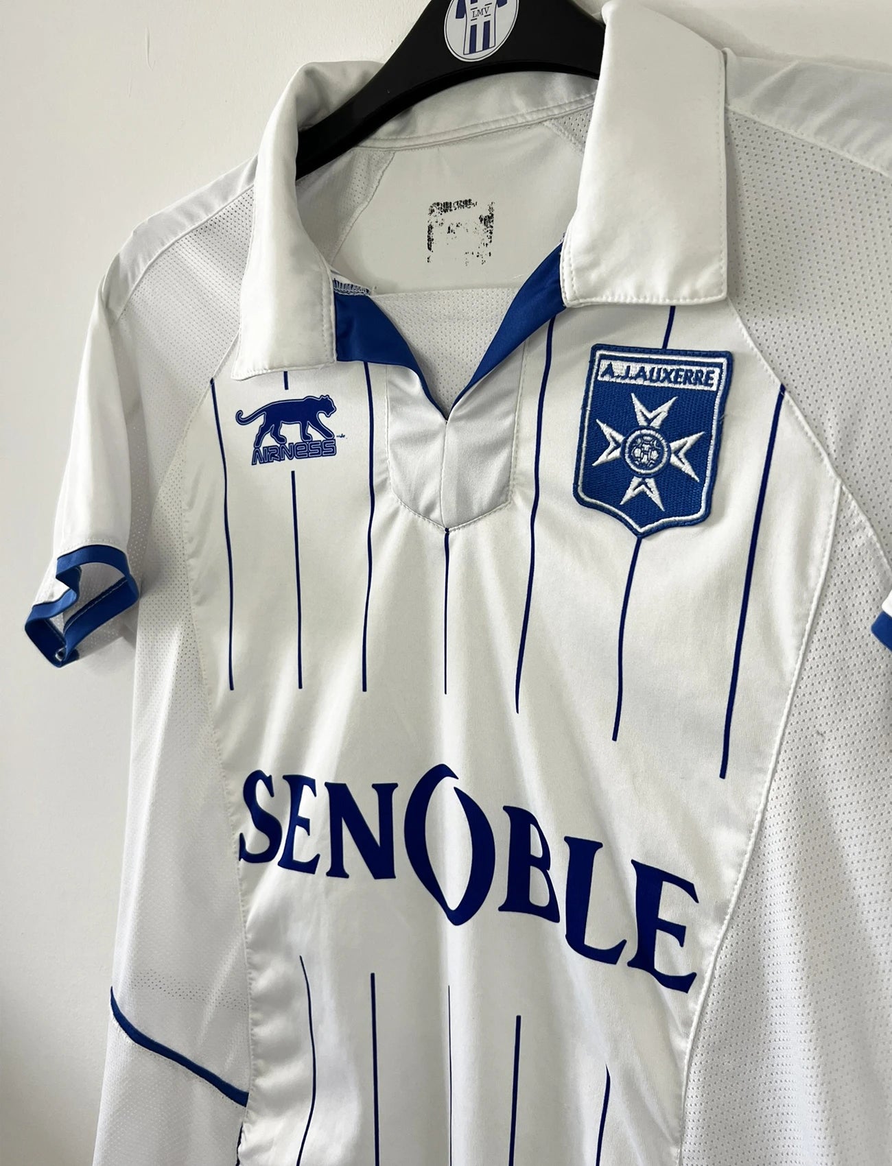 Maillot de foot vintage domicile blanc de l'AJ Auxerre de la saison 2010-2011. On peut retrouver l'équipementier airness et le sponsor senoble. Il s'agit d'un maillot authentique d'éppoque.