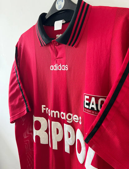 Maillot de foot vintage domicile rouge de Guingamp 1996/1997. On peut retrouver l'équipementier Adidas et le sponsor Fromages Rippoz. Il s'agit d'un maillot authentique d'époque.