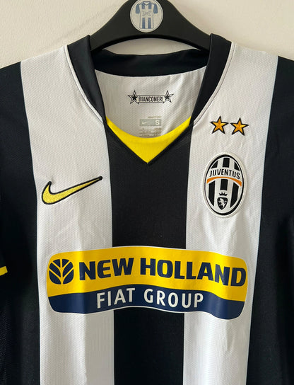 Maillot de foot vintage domicile blanc et noir de la Juventus 2008/2009. On peut retrouver l'équipementier Nike et le sponsor New Holland. Il s'agit d'un maillot authentique d'époque.