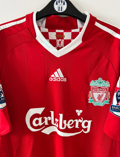 Maillot de foot vintage domicile rouge de Liverpool 2008/2009. On peut retrouver l'équipementier Adidas et le sponsor Carlsberg. Le maillot est floqué du numéro 23 Carragher. Il s'agit d'un maillot authentique d'époque.