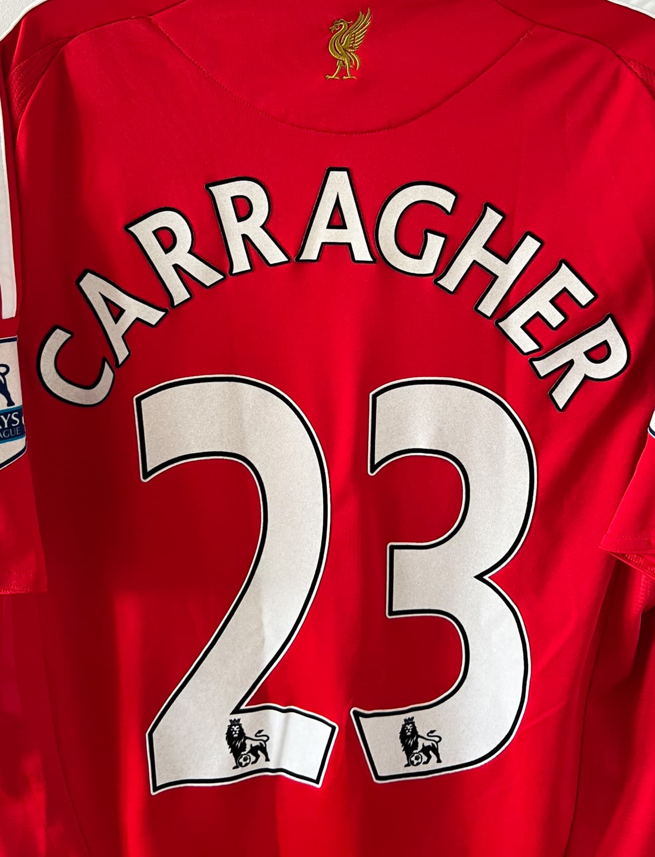 Maillot de foot vintage domicile rouge de Liverpool 2008/2009. On peut retrouver l'équipementier Adidas et le sponsor Carlsberg. Le maillot est floqué du numéro 23 Carragher. Il s'agit d'un maillot authentique d'époque.