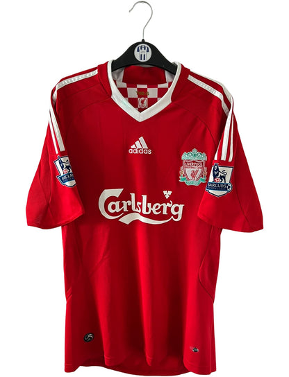 Maillot de foot vintage domicile rouge de Liverpool 2008/2009. On peut retrouver l'équipementier Adidas et le sponsor Carlsberg. Le maillot est floqué du numéro 23 Carragher. Il s'agit d'un maillot authentique d'époque.